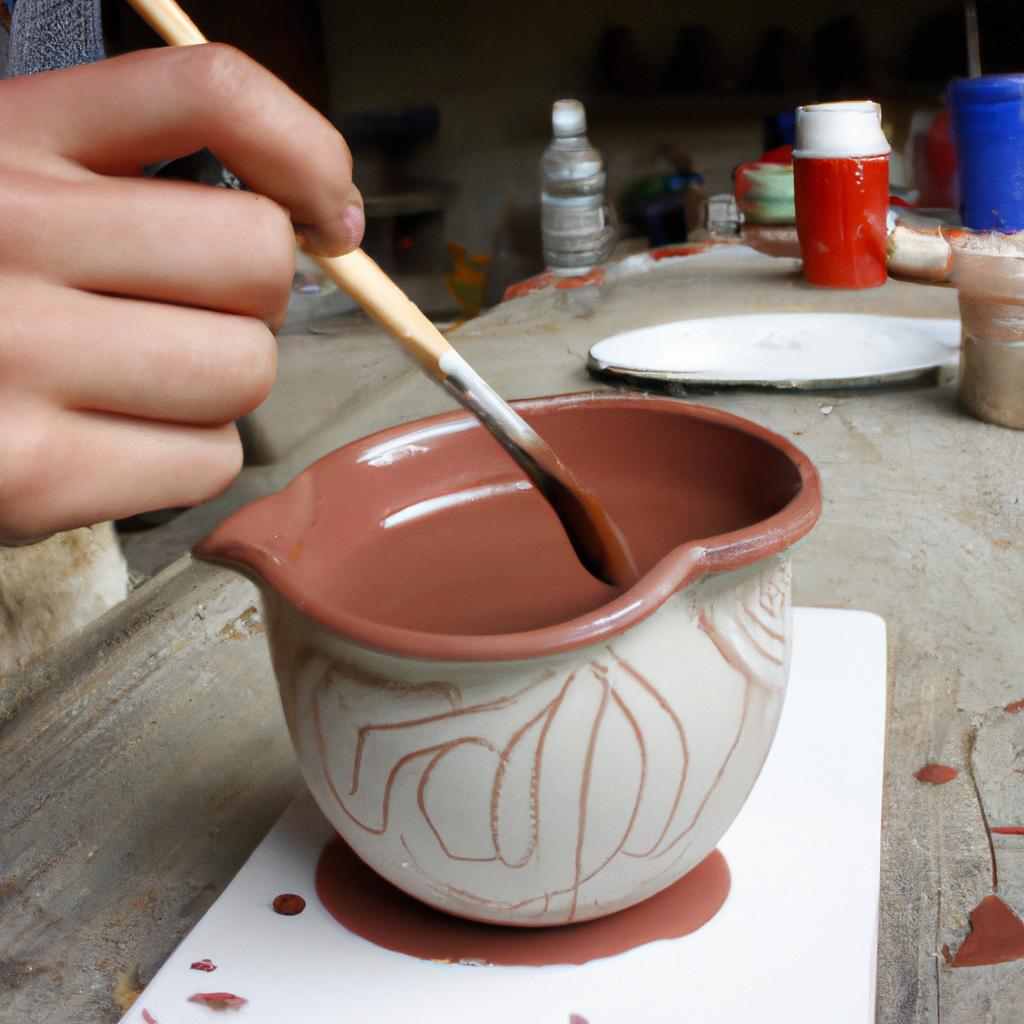 Person applying glaze to pottery