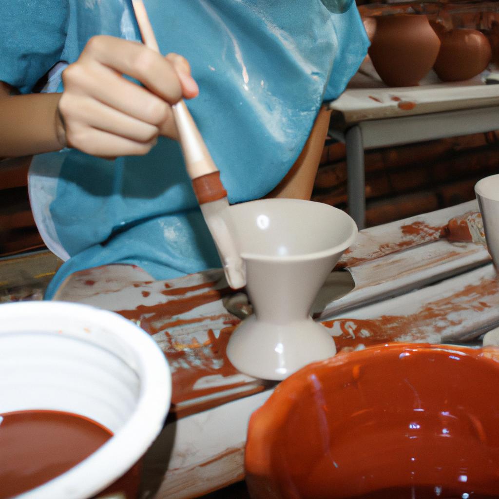 Person applying glaze to pottery